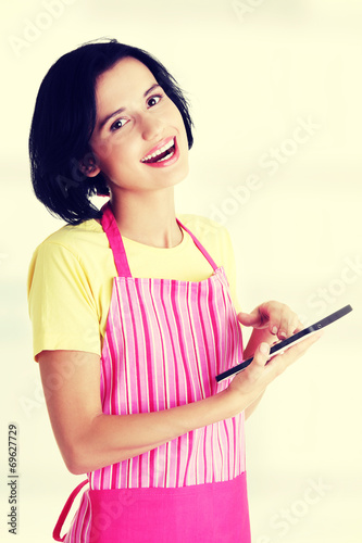 Young woman in pink apron using tablet computer
