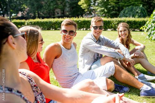 group of smiling friends outdoors sitting in park