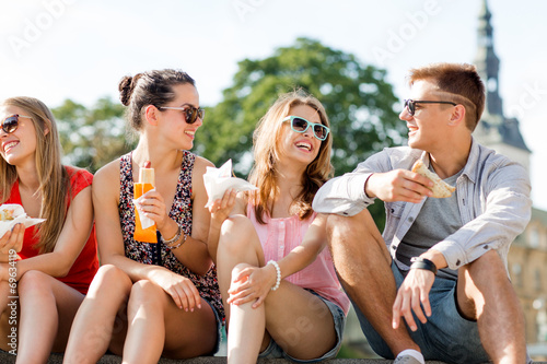 group of smiling friends sitting on city square © Syda Productions