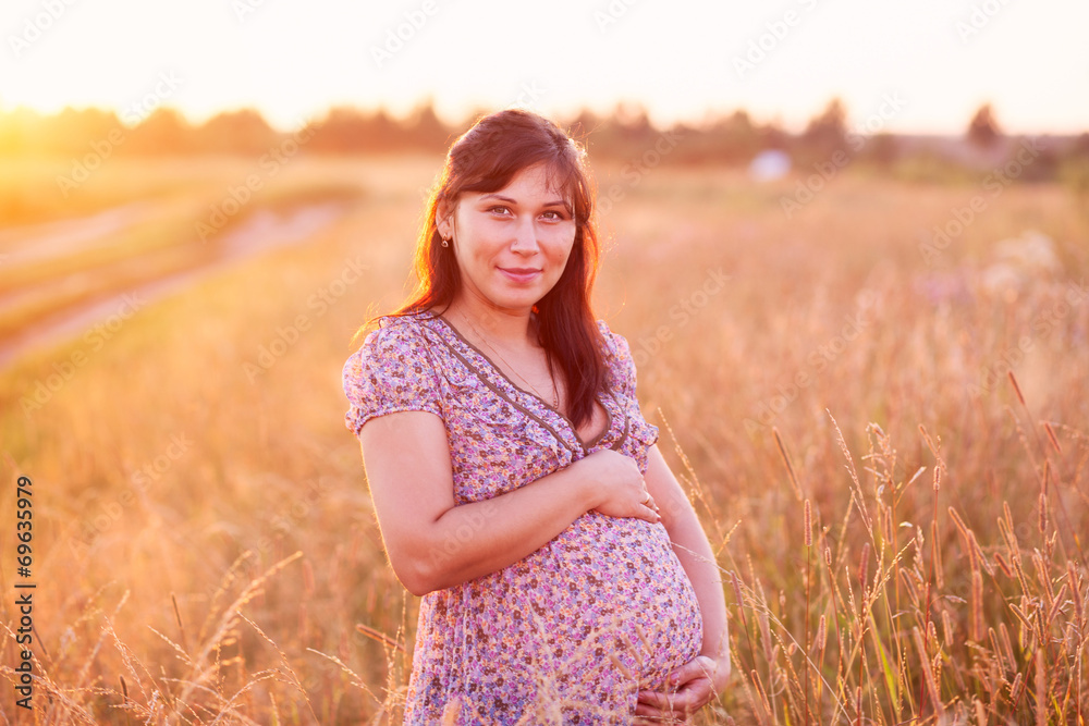 Beautiful happy young pregnant woman girl in field holding belly Beautiful happy young pregnant woman girl in field holding belly