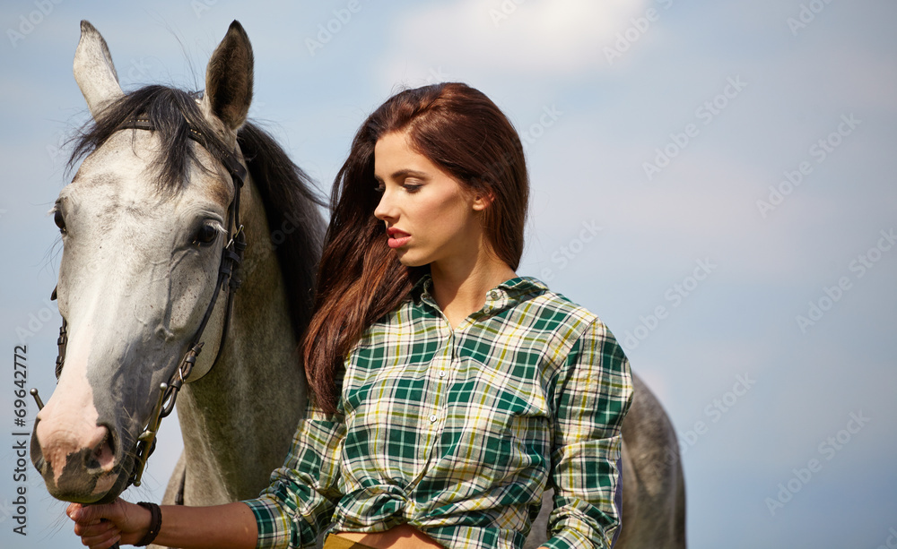 Obraz premium An attractive young woman with a horse