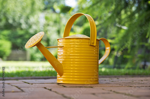 Photo Orange watering can in the garden