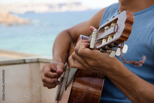 guy playing guitar on a balcony on the sea