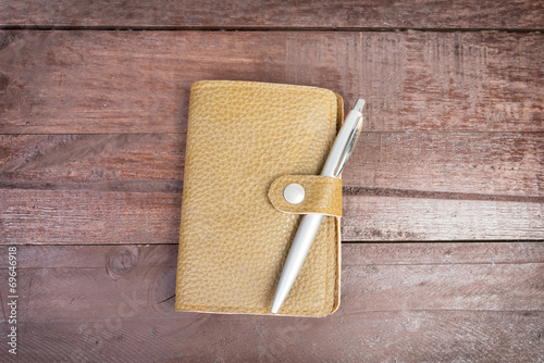 Pen on top of yellow organizer with leather cover