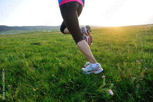 Runner athlete legs running on sunset grass seaside
