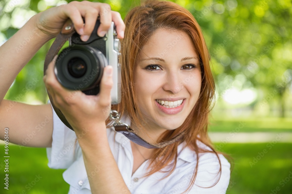 Pretty redhead taking a photo in the park Pretty redhead taking a photo in the park