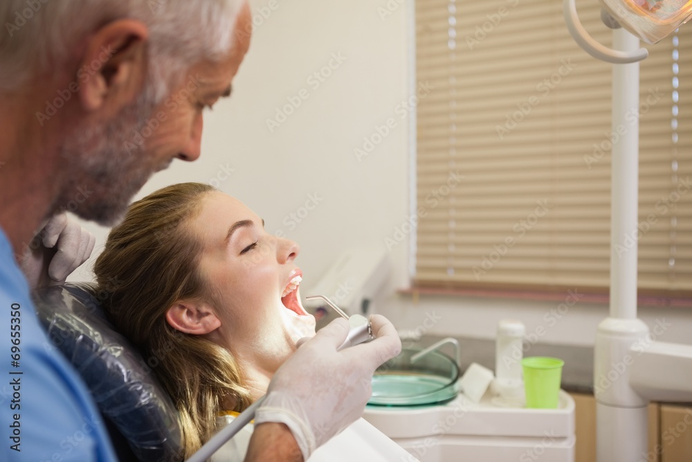 Dentist examining a patients teeth Dentist examining a patients teeth