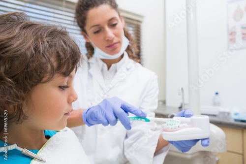 Pediatric dentist showing little boy how to brush his teeth