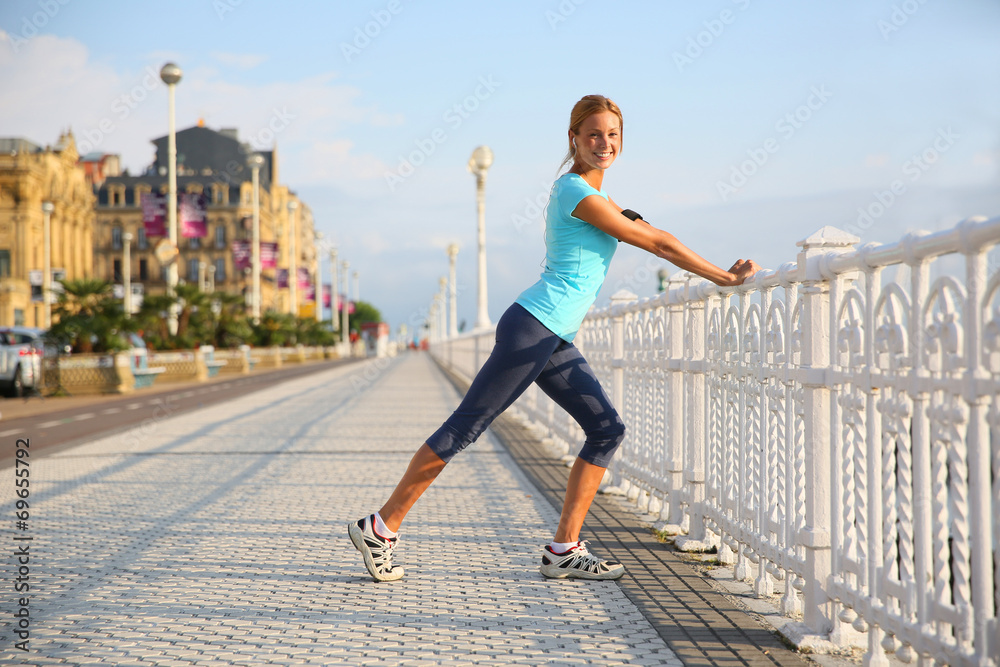 Woman in town stretching out after running Woman in town stretching out after running