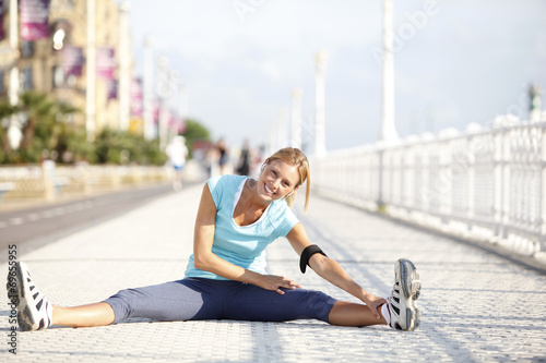 Cheerful jogger stretching after exercising in the street