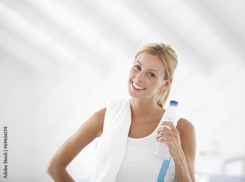 Fitness girl holding bottle of water after exercising Fitness girl holding bottle of water after exercising