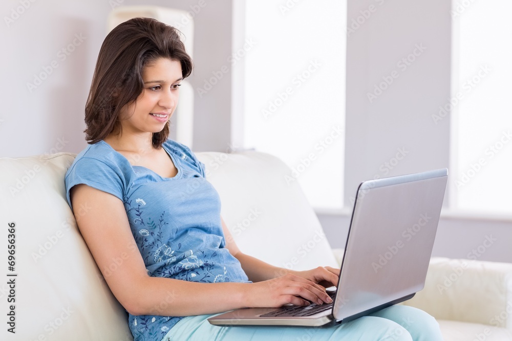 Pretty brunette relaxing on the couch using laptop Pretty brunette relaxing on the couch using laptop