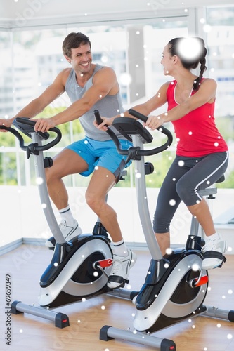 Fototapeta Naklejka Na Ścianę i Meble -  Smiling young couple working out at spinning