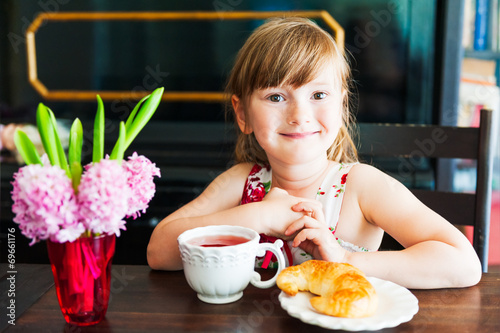 Adorable little girl drinking tea at home