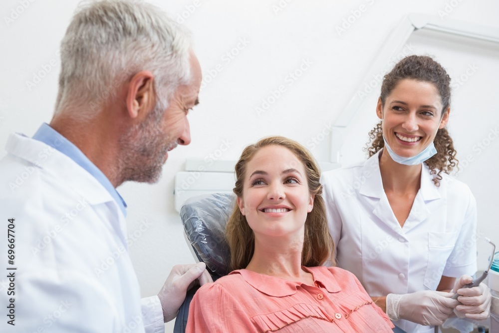 Fototapeta premium Dentist talking with patient while nurse prepares the tools