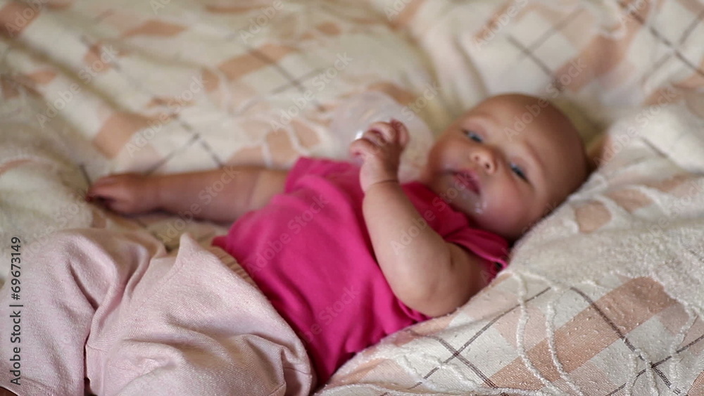 little baby lying on the bed and drinking milk from a bottle little baby lying on the bed and drinking milk from a bottle