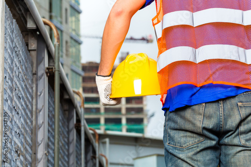 Worker on construction site with helmet or hard hat photo