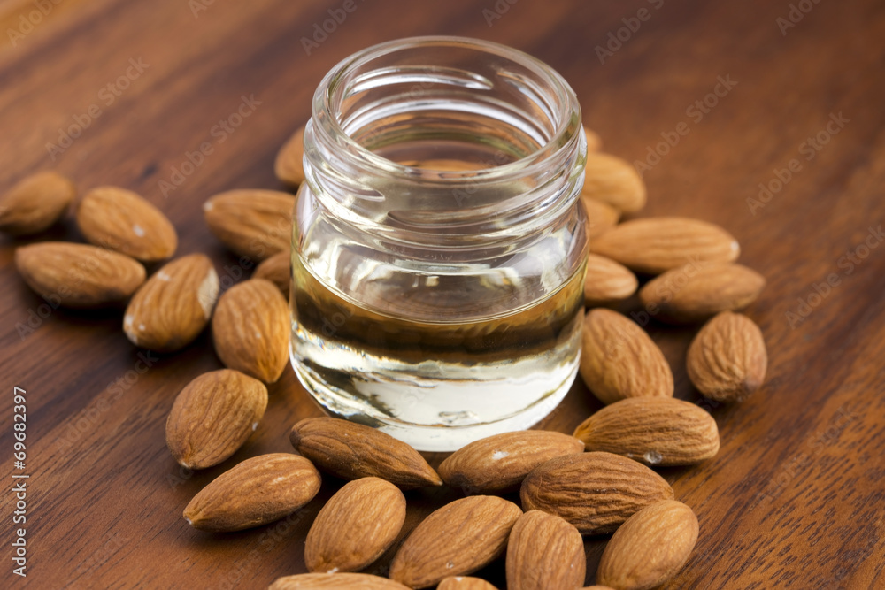 Almond oil with nuts on wooden background Almond oil with nuts on wooden background