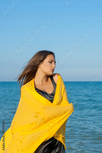 Young sad girl near sea on sunset