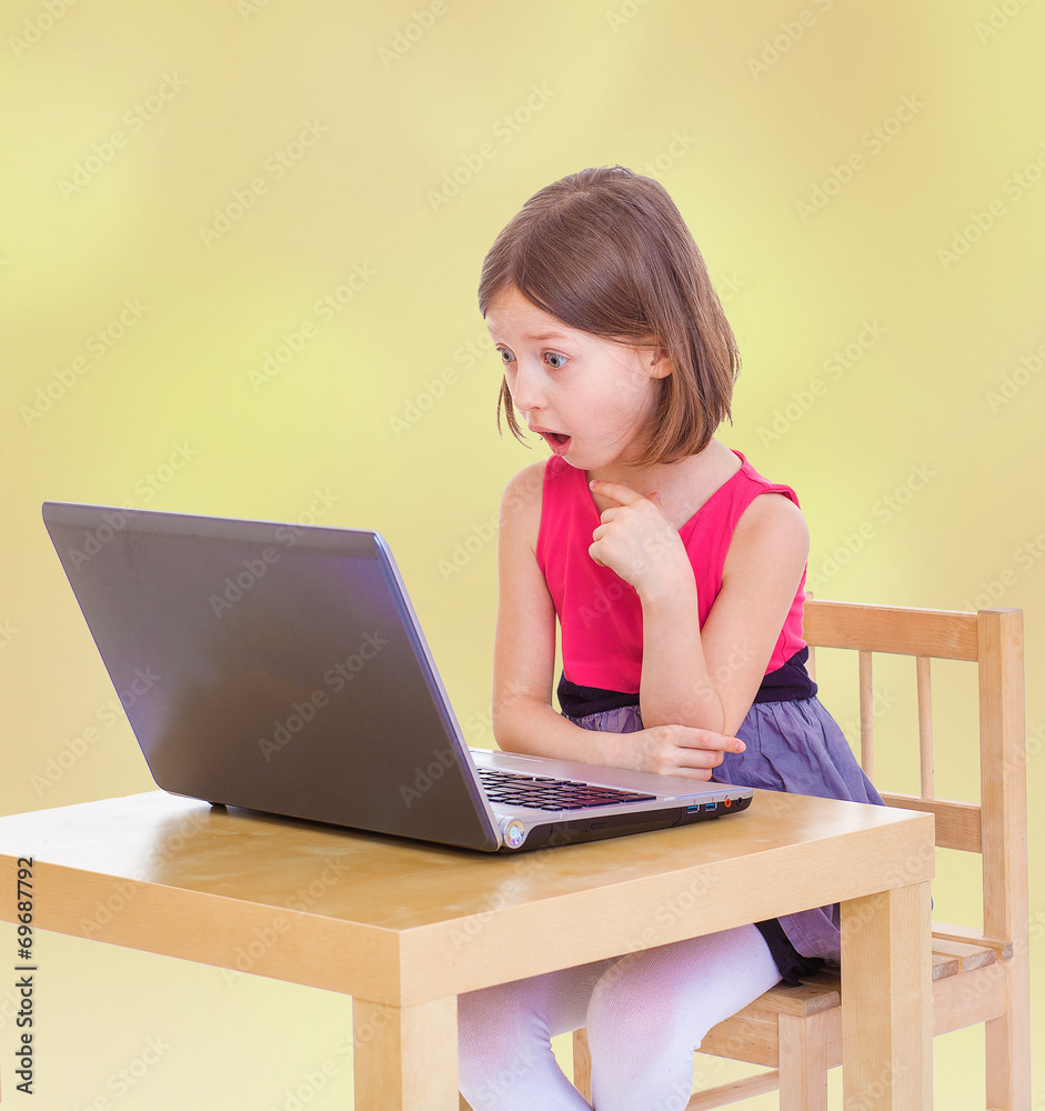 Surprised little girl looking into the computer. Surprised little girl looking into the computer.