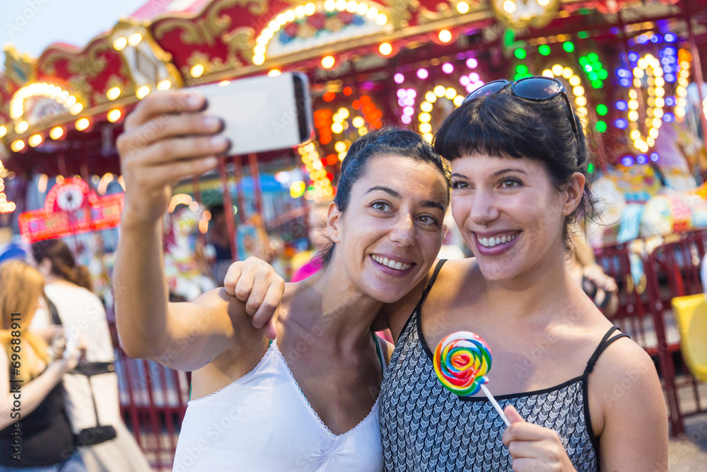 Fototapeta premium Happy Young Women Taking Selfie at Luna Park