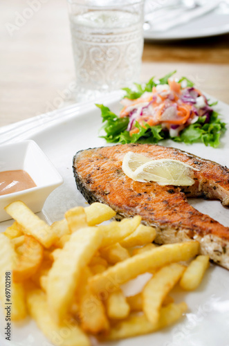 grilled salmon steak served with salad, chips,