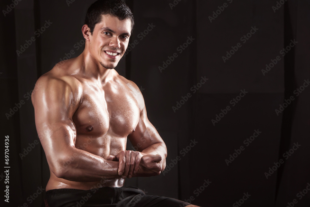 Muscular male bodybuilder, on a dark background. Muscular male bodybuilder, on a dark background.