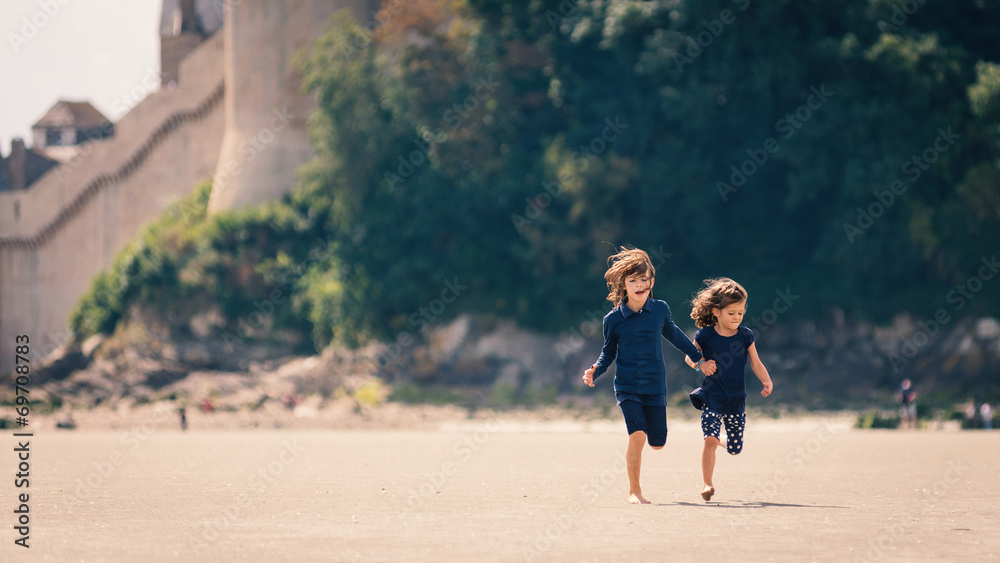 Young sisters running on the beach in front of Mont Saint Michel Young sisters running on the beach in front of Mont Saint Michel