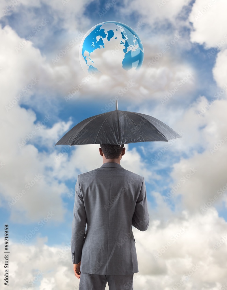Composite image of businessman standing under umbrella Composite image of businessman standing under umbrella