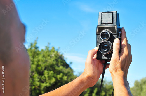 Tableau sur toile young man taking a selfie with an old medium format camera