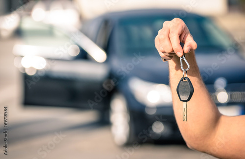 Man's hand holding modern car keys ready for rental