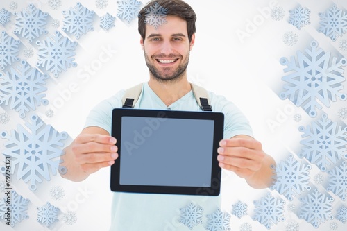 Composite image of handsome student showing his tablet pc