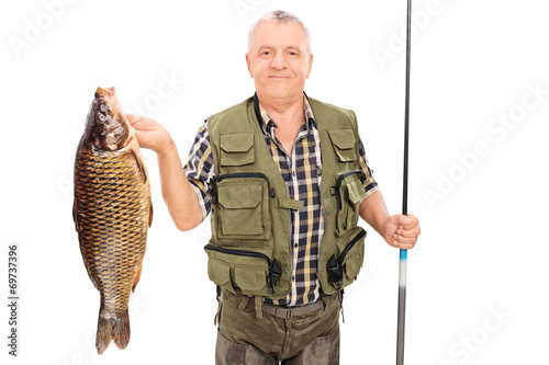 Mature fisherman holding big fish and fishing rod