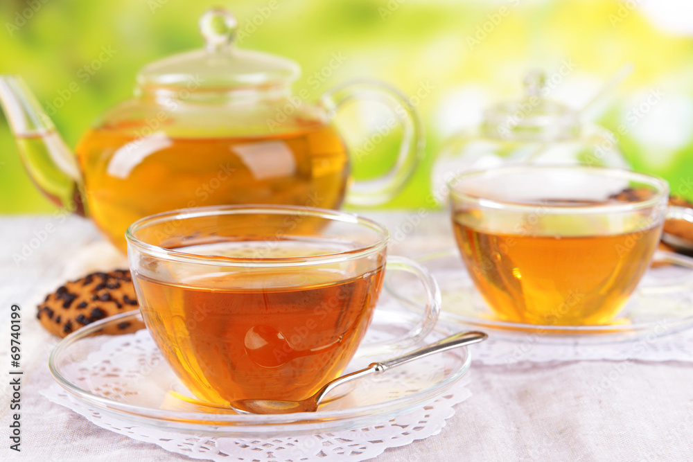 Teapot and cups of tea on table on bright background Teapot and cups of tea on table on bright background