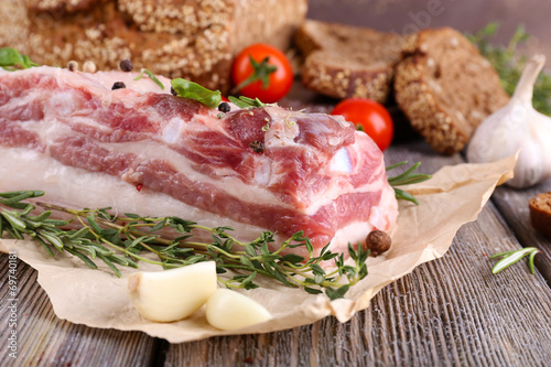 raw bacon with bread and spices on wooden table