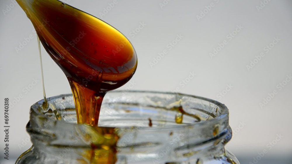 Closeup of honey pot with drizzler dripping honey Closeup of honey pot with drizzler dripping honey