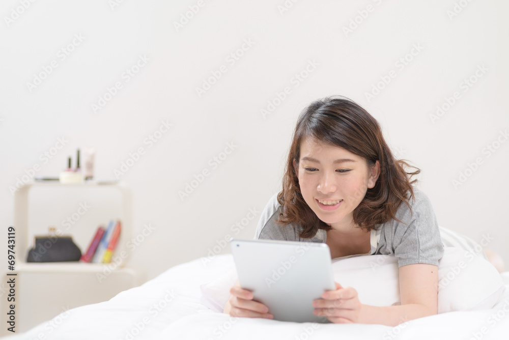 ベッドでタブレットPCを使う女性 ベッドでタブレットPCを使う女性