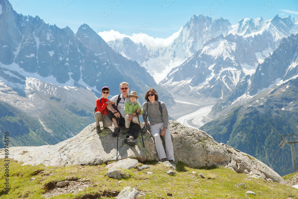 Family (grandfather, father and two boys) rest on summer Alps