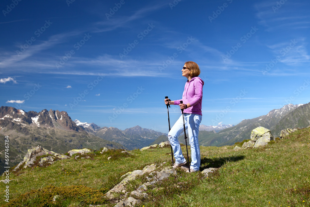 Portrait of a young woman with trekking poles in Alps