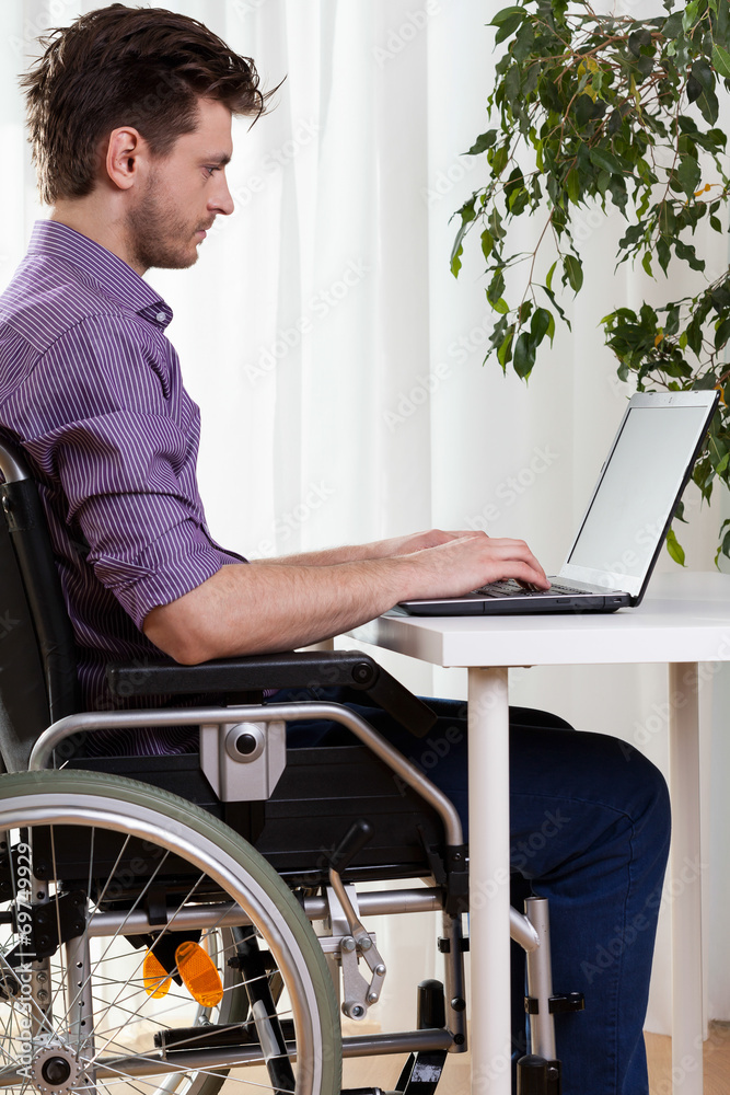 Man on wheelchair working on laptop Man on wheelchair working on laptop