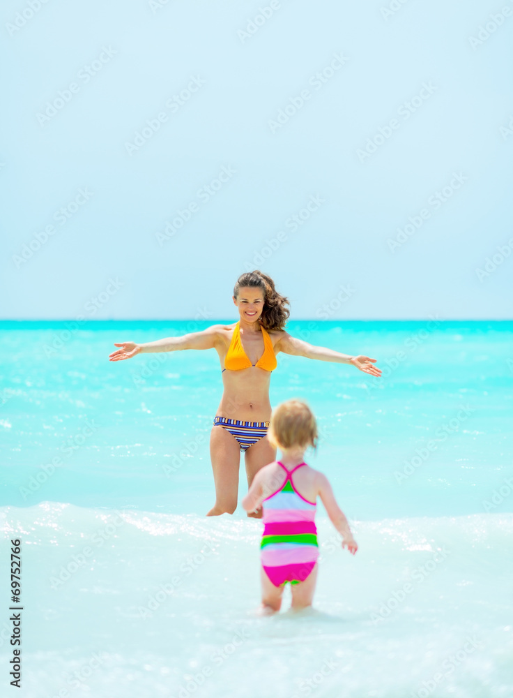Mother playing with baby girl in sea