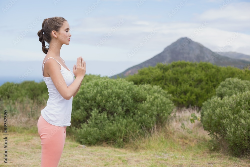 Woman with hands joined standing on countryside landscape Woman with hands joined standing on countryside landscape