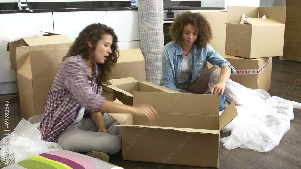 Two Women Moving Into New Home And Unpacking Boxes Two Women Moving Into New Home And Unpacking Boxes