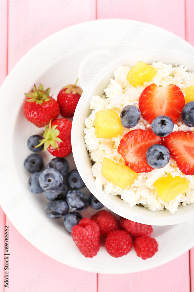 Cottage cheese with fruits and berries in bowl on wooden table