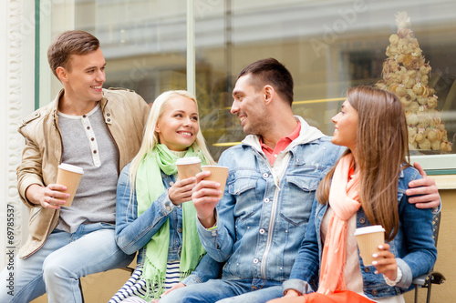 group of smiling friends with take away coffee