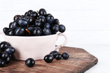 Purple grapes in bowl on wooden background