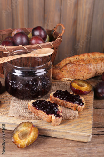 Bread with plum jam on wooden table close-up