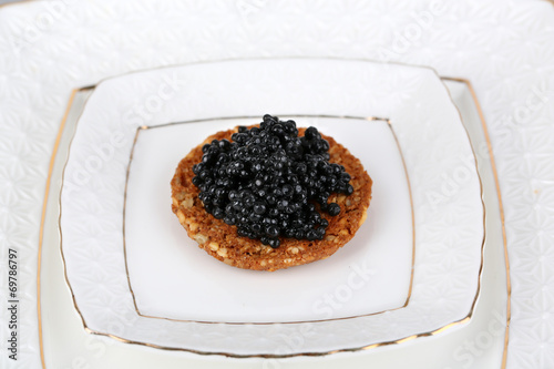 Black caviar on crispy bread on plate