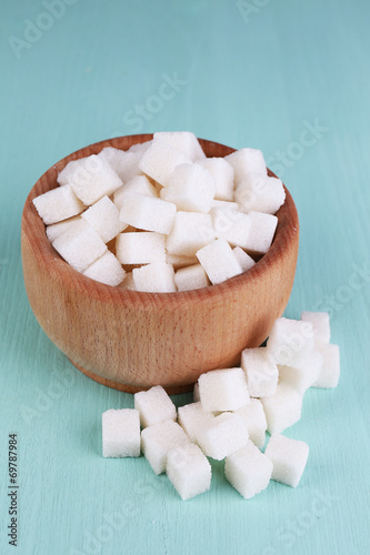 White refined sugar in wooden bowl on color wooden background
