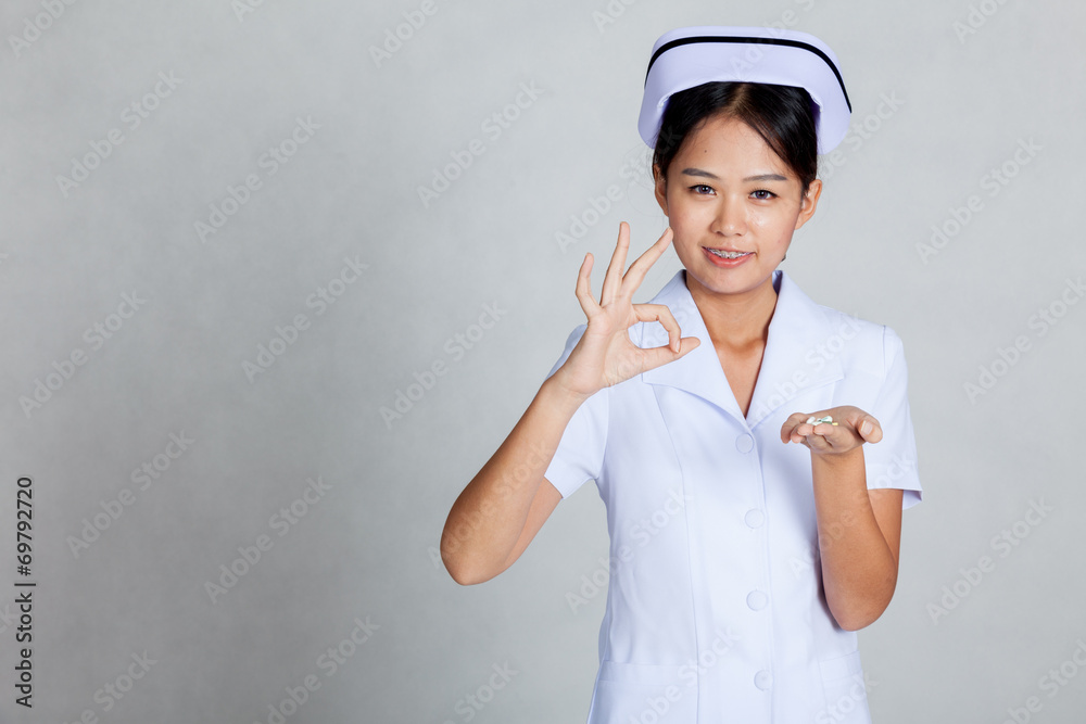 Young Asian nurse show OK with pills on her palm hand Young Asian nurse show OK with pills on her palm hand